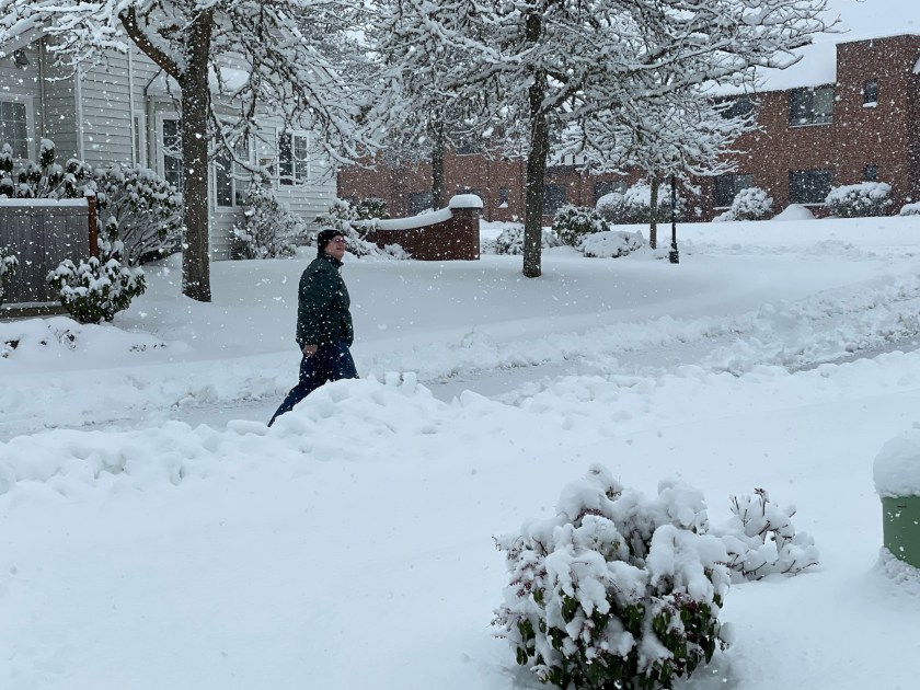 man walking outside while snow continues to fall