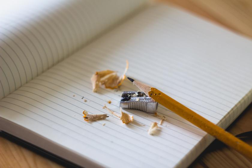 wooden pencil on blank notebook page, with small pencil sharpener and wooden shavings